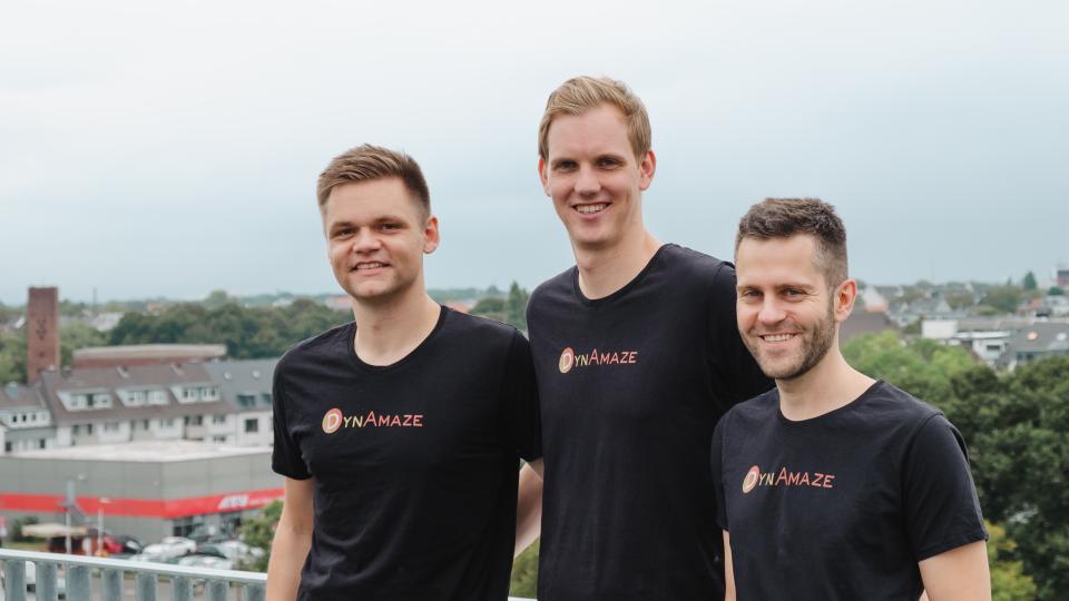 The three founders of DynAmaze standing next to each other on a balcony